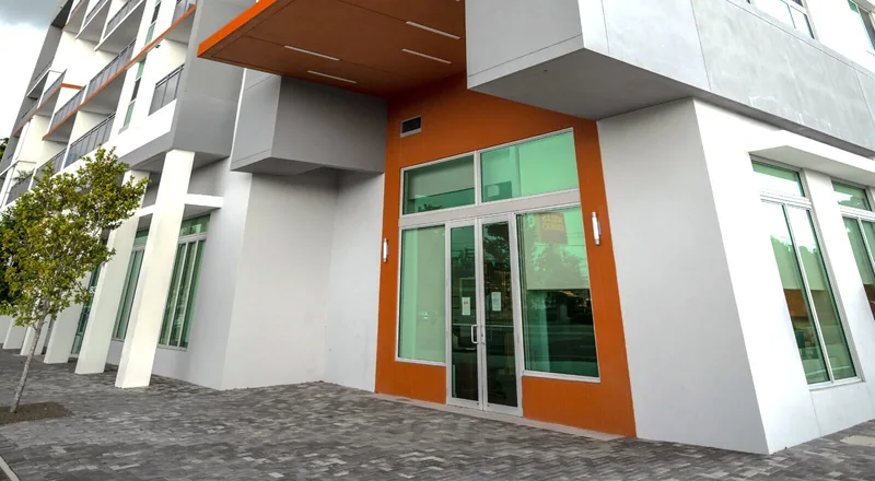 Storefront framing with green-tinted glass and commercial double doors.